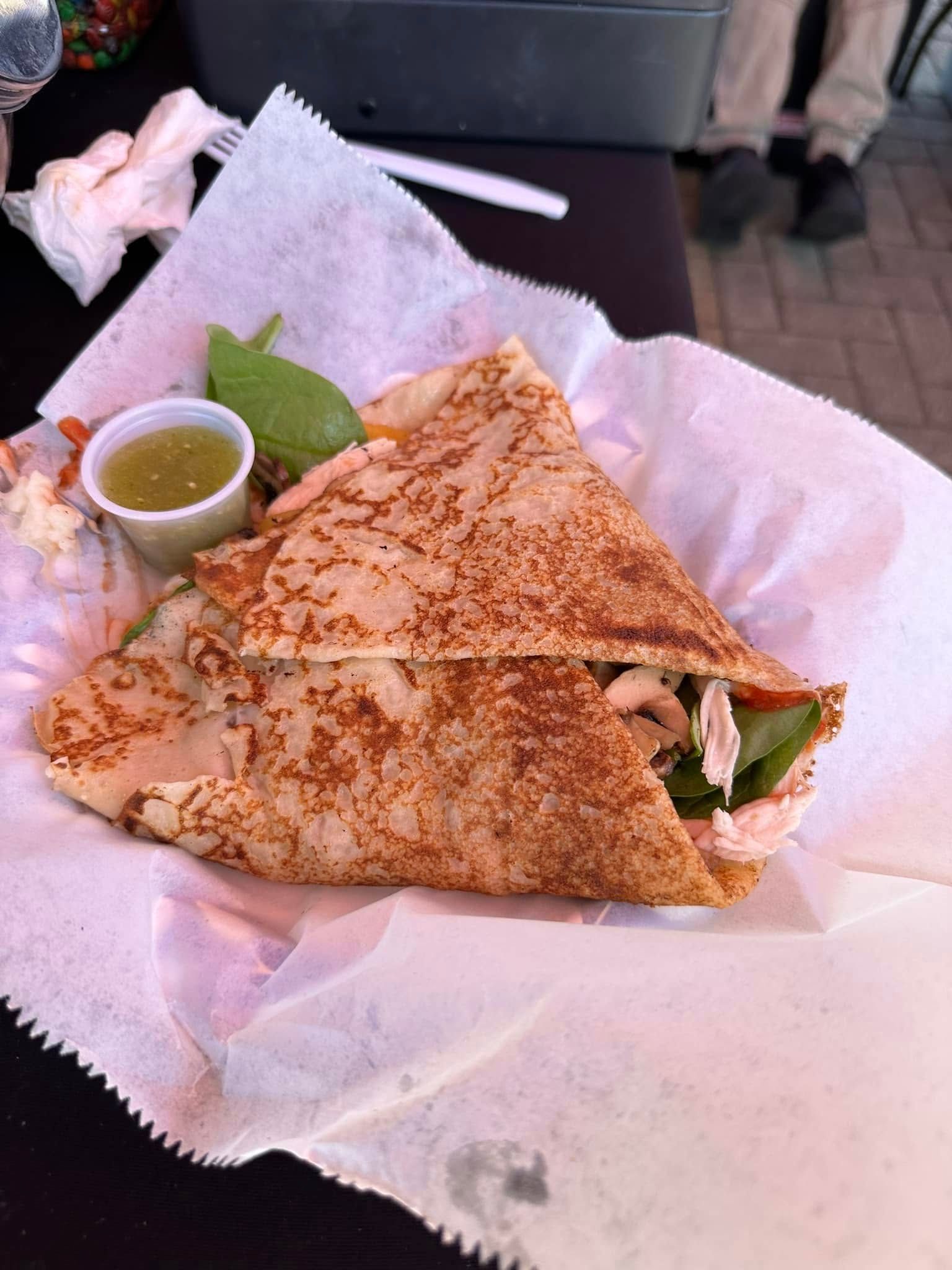 Grilled quesadilla halves on pink paper with salsa and lime on a table.