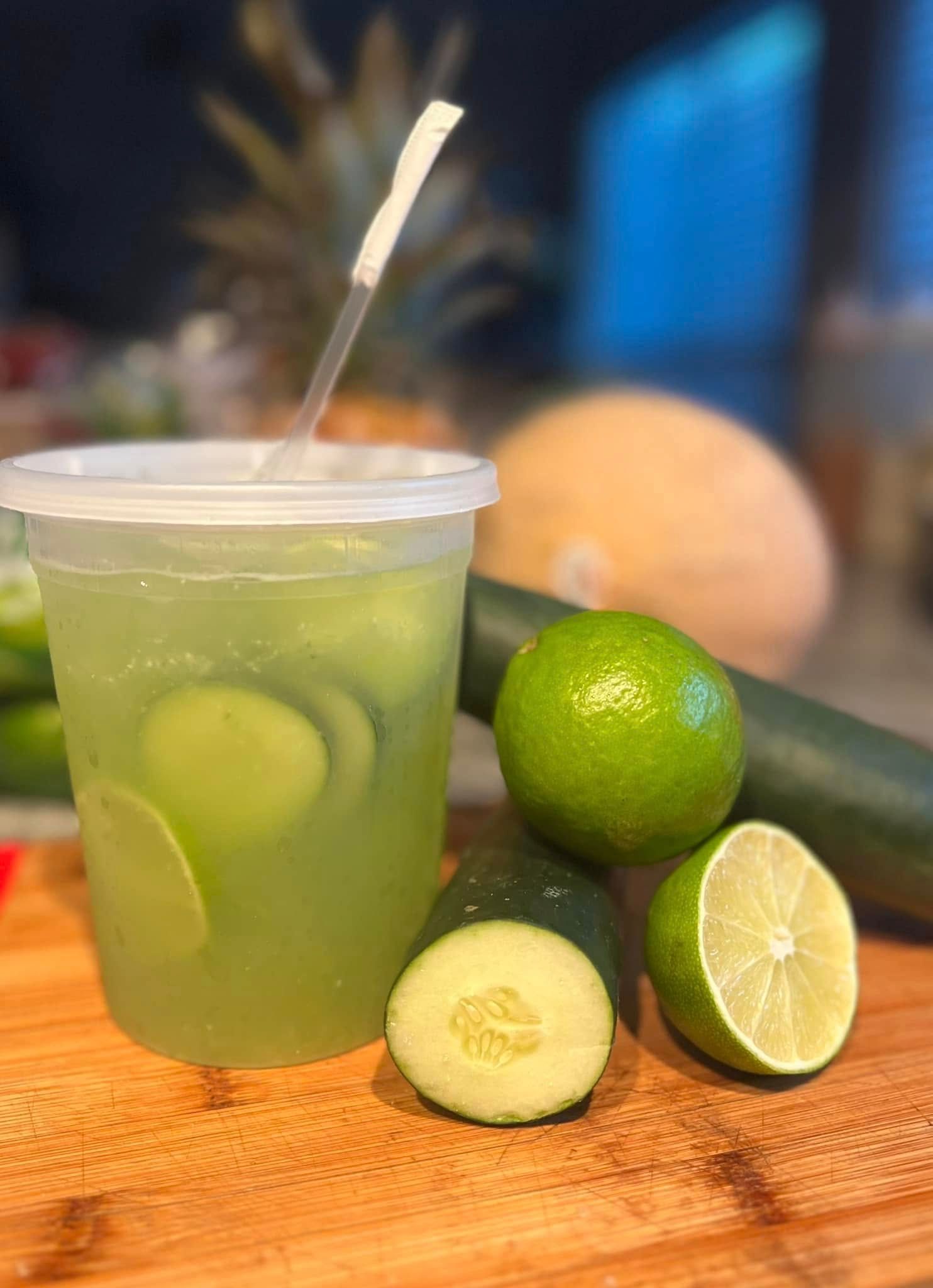 Green lime drink with lime slices and whole limes on a wooden table