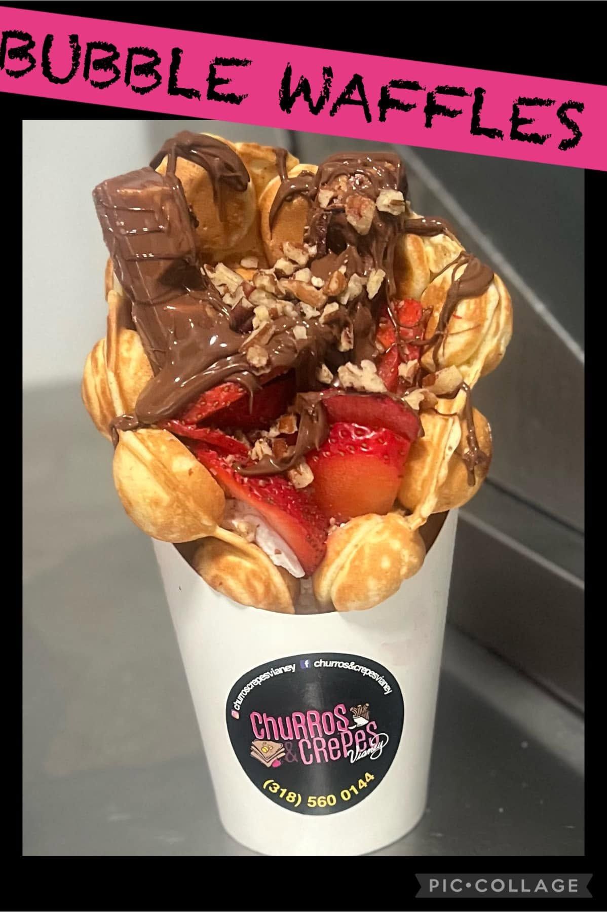 Bubble waffles topped with chocolate and strawberries in a branded cup, with a pink “BUBBLE WAFFLES” sign.