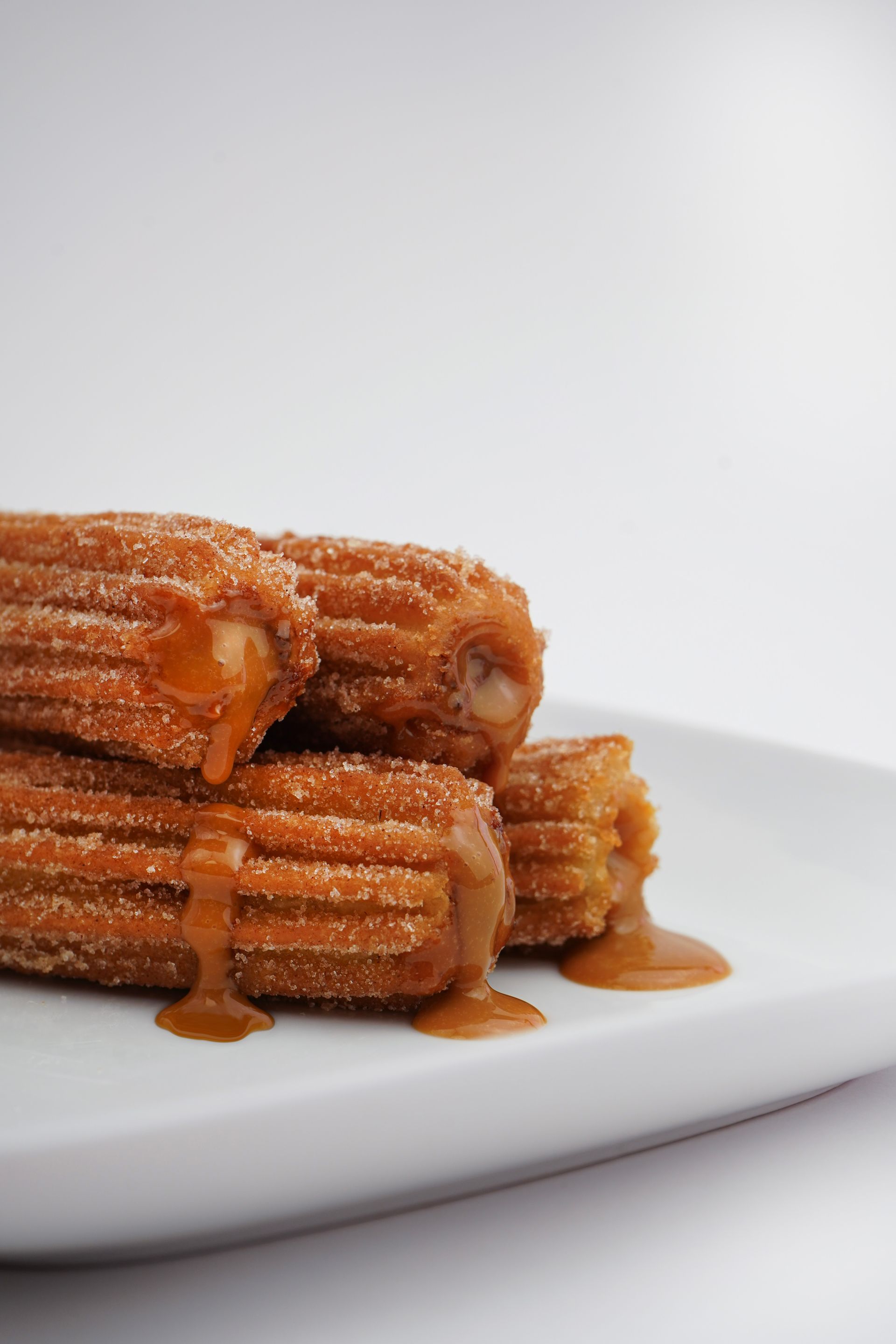 Stack of caramel-drizzled churros on a white plate