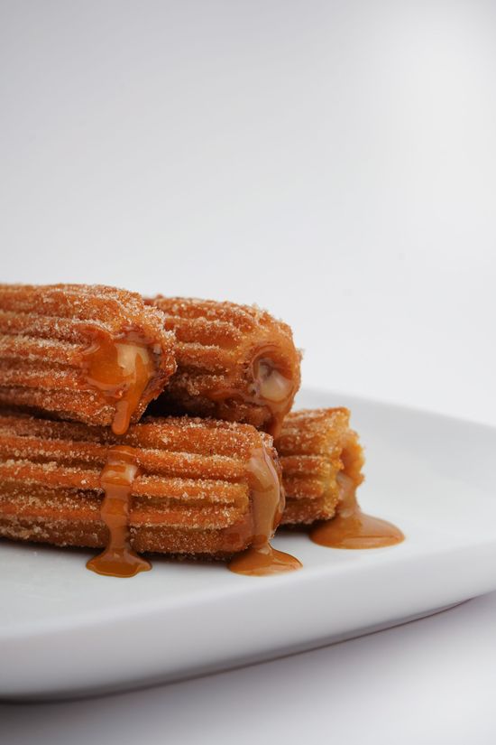 Stack of caramel-drizzled churros on a white plate