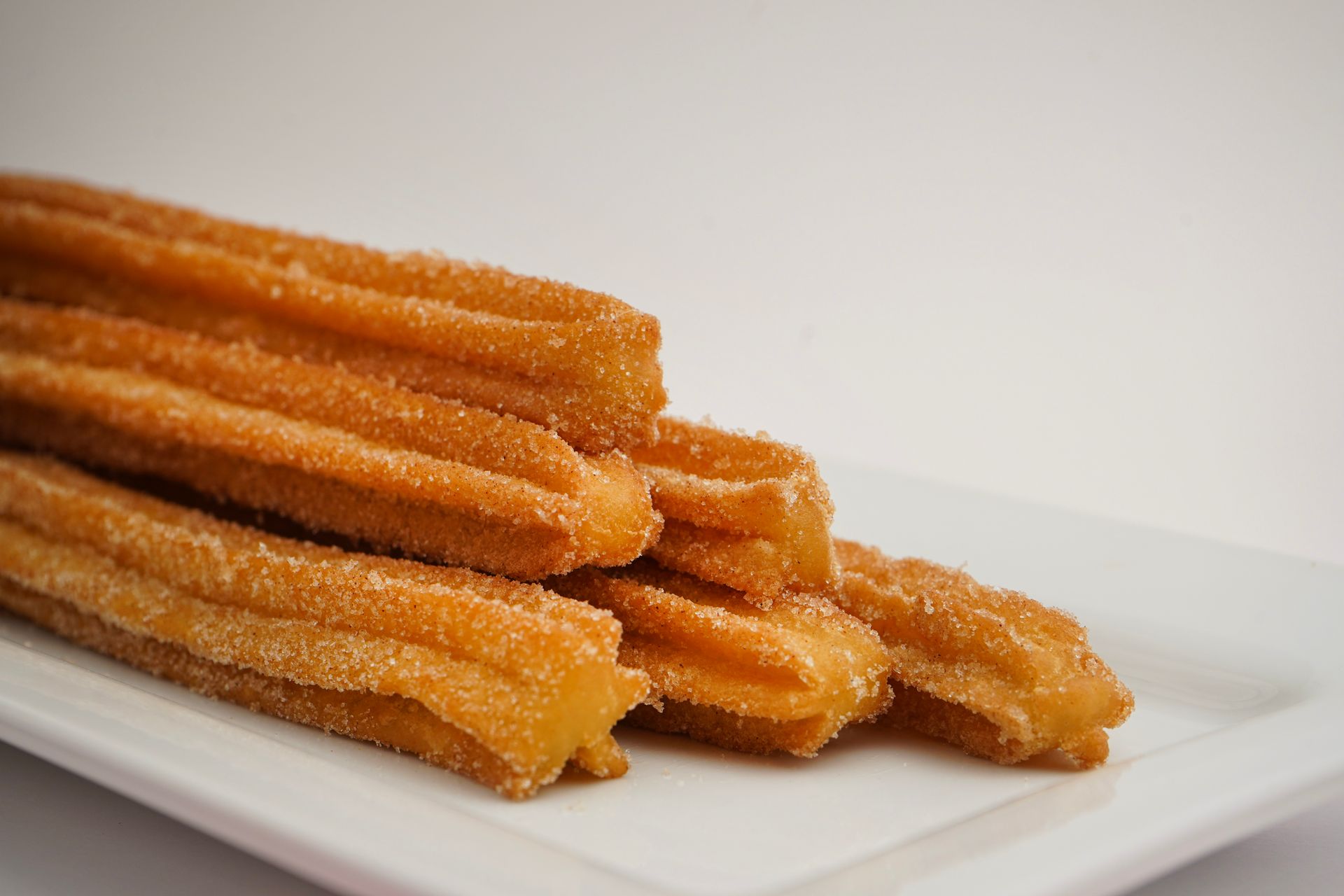 Stack of golden churros on a white plate