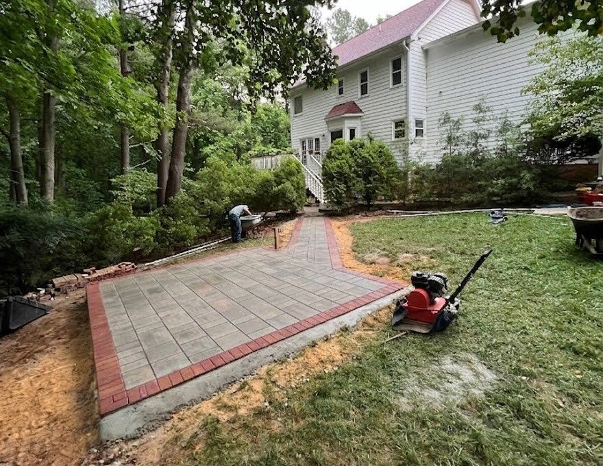 Stone patio beside a white house with wooden steps, deck seating, and large windows