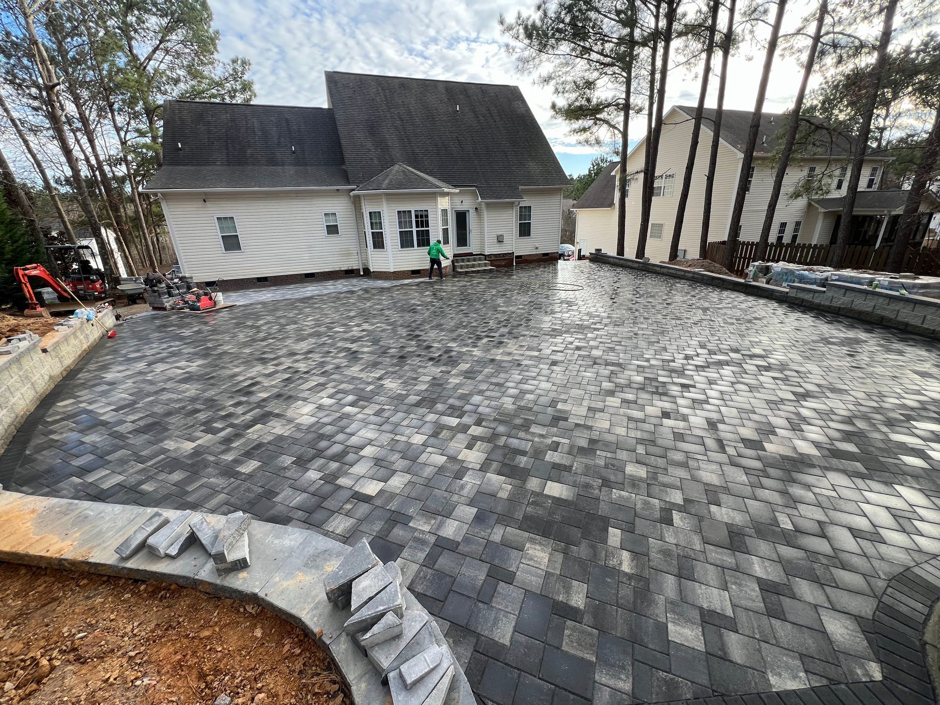 Newly paved gray paver driveway in front of a white house with a garage.