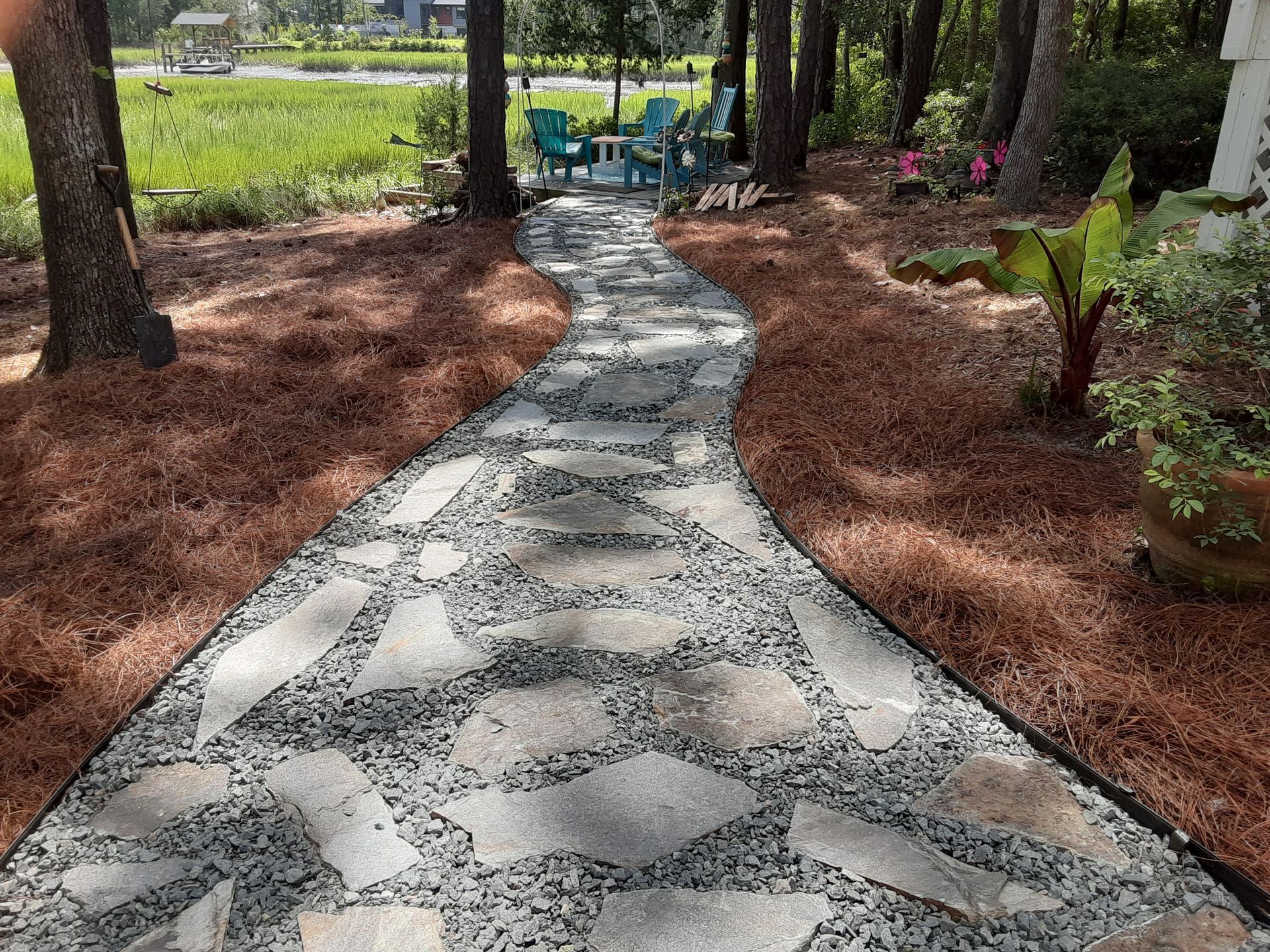 Curving stone path through a landscaped garden with trees and reddish mulch