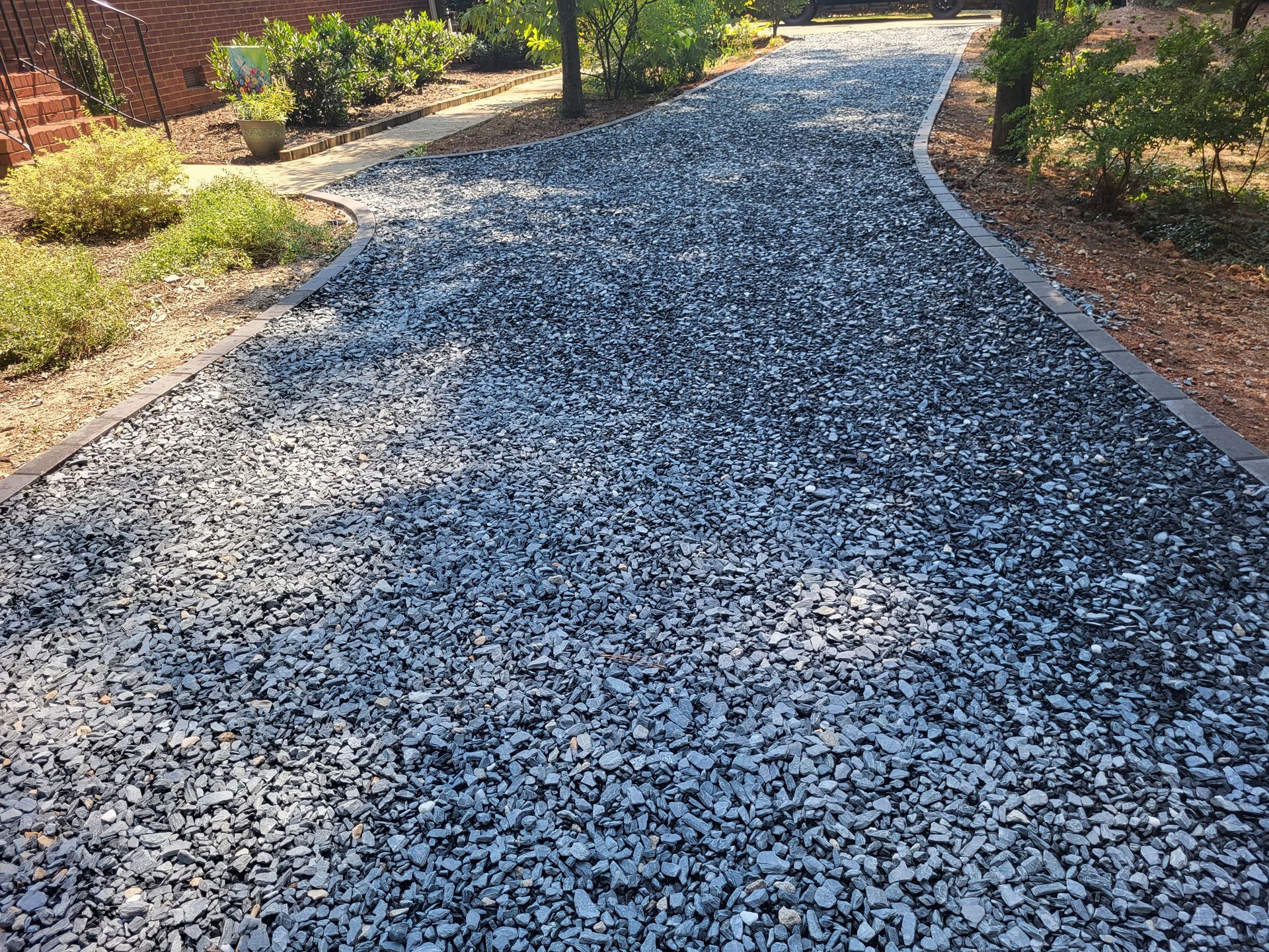 Gravel garden path curving through landscaped greenery in warm sunlight