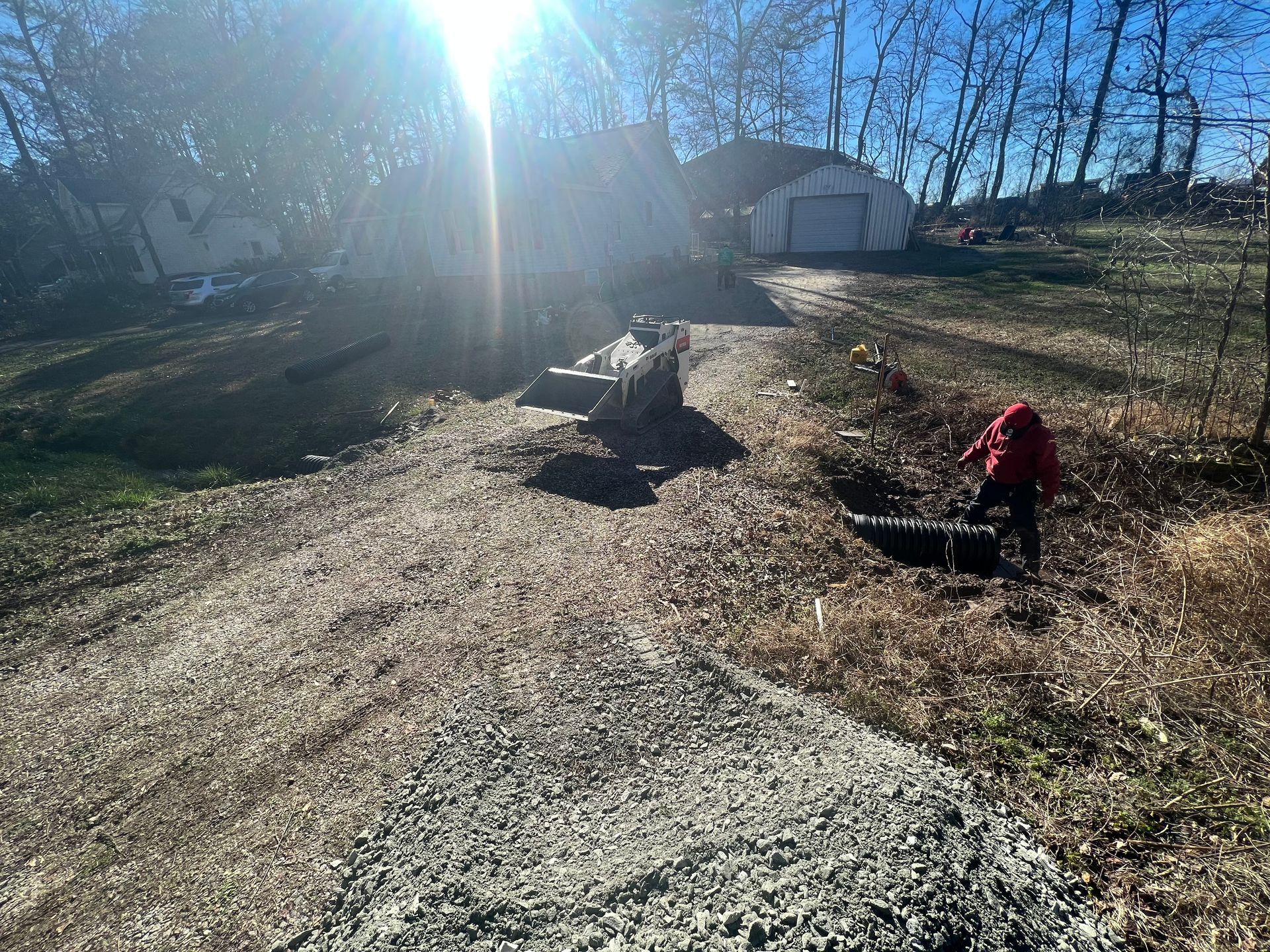 Sunlit backyard with two black chickens near a gravel path and a red object on the right