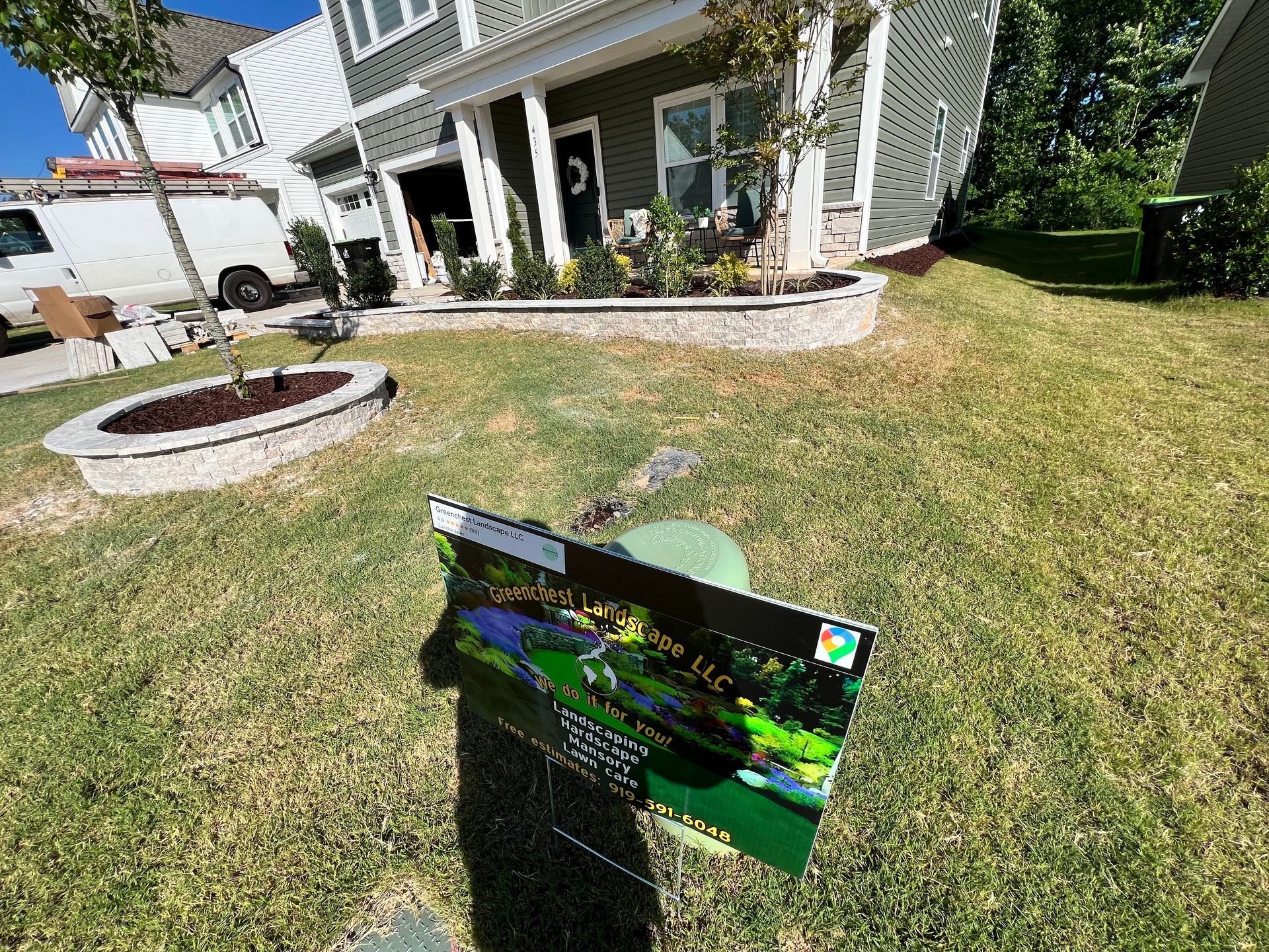 Backyard lawn with a small sign in the foreground and a house patio in the background