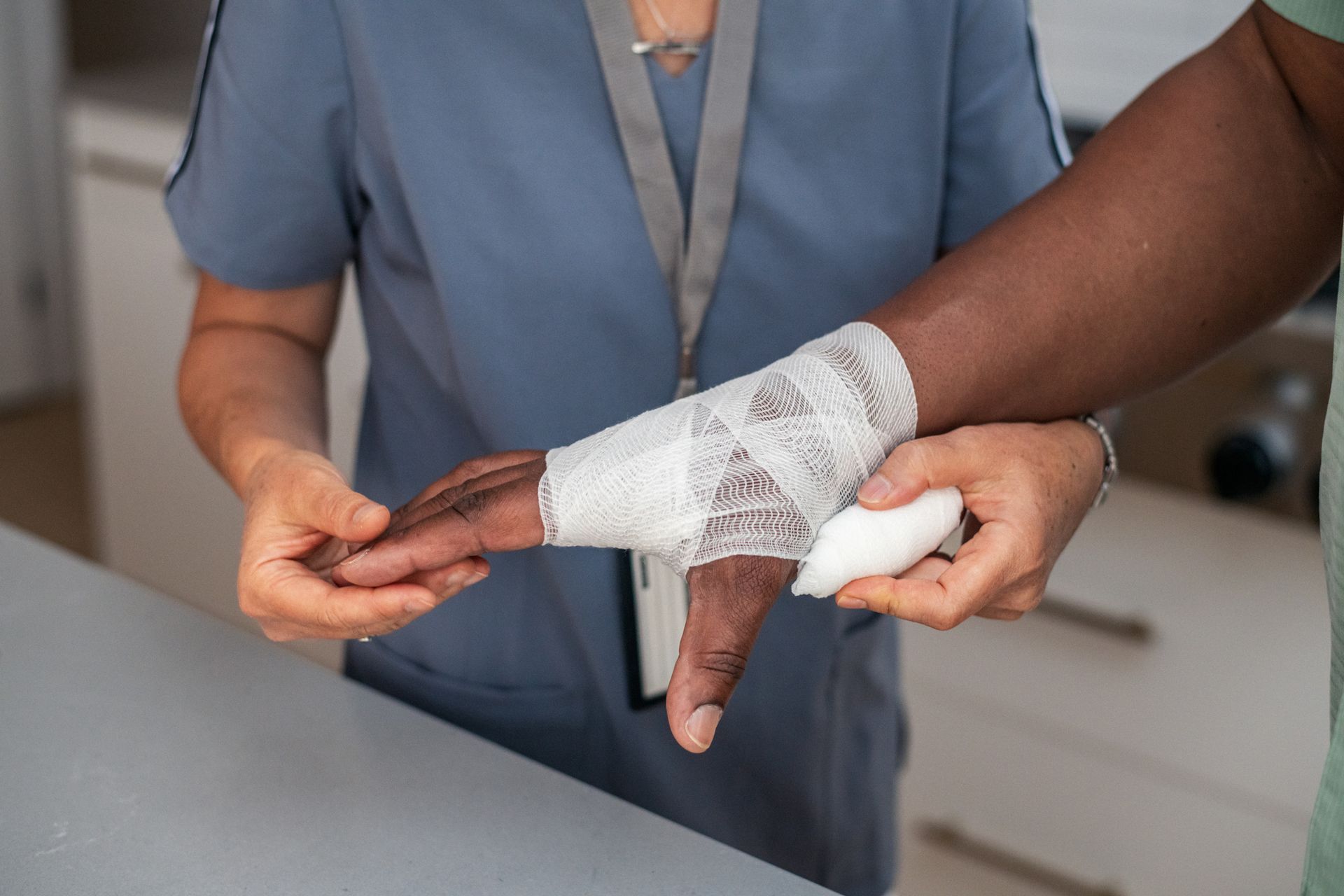 A nurse is wrapping a patient 's wrist with a bandage.