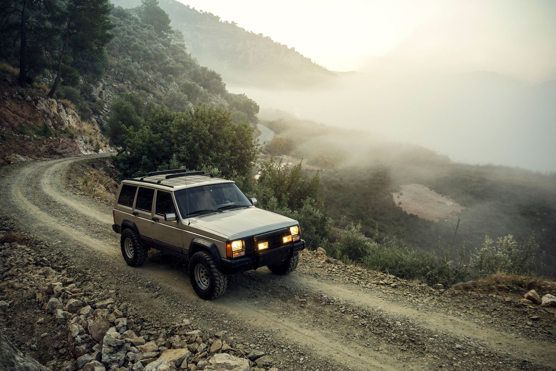 A jeep is driving down a dirt road in the mountains.