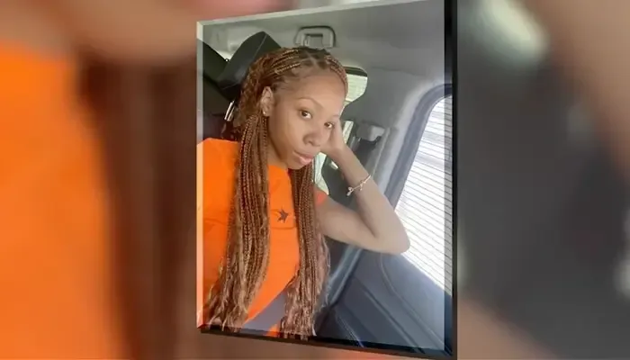 A woman is sitting in a car wearing an orange vest.