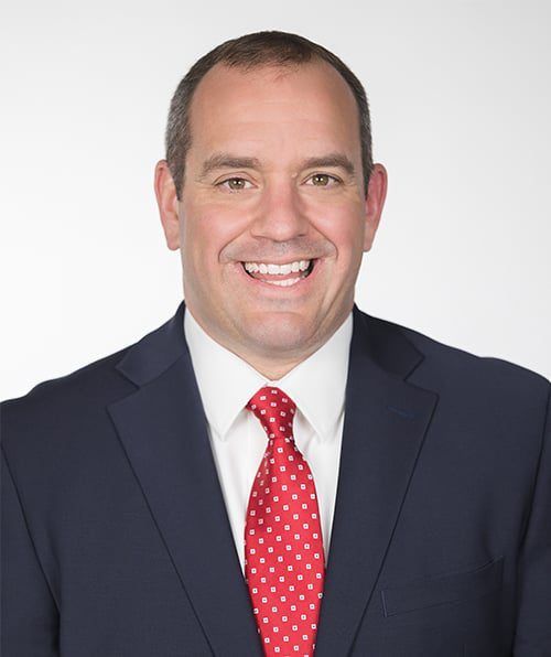 A man in a suit and tie is smiling for the camera