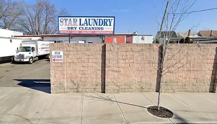 A sign for star laundry dry cleaning is above a brick wall.