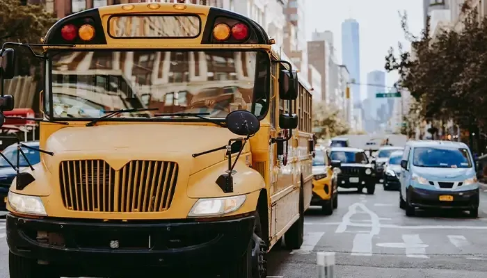 A yellow school bus is driving down a city street.
