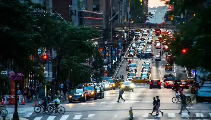 A busy city street at night with people crossing the street.