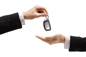 A man in a suit is handing a car key to another man.