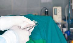 A surgeon is holding a pair of scissors in an operating room.
