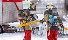 Two firefighters are spraying foam from a hose at a fire.