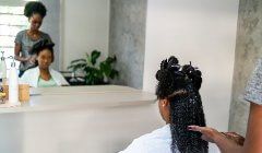 A woman is getting her hair done by a hairdresser in a salon.