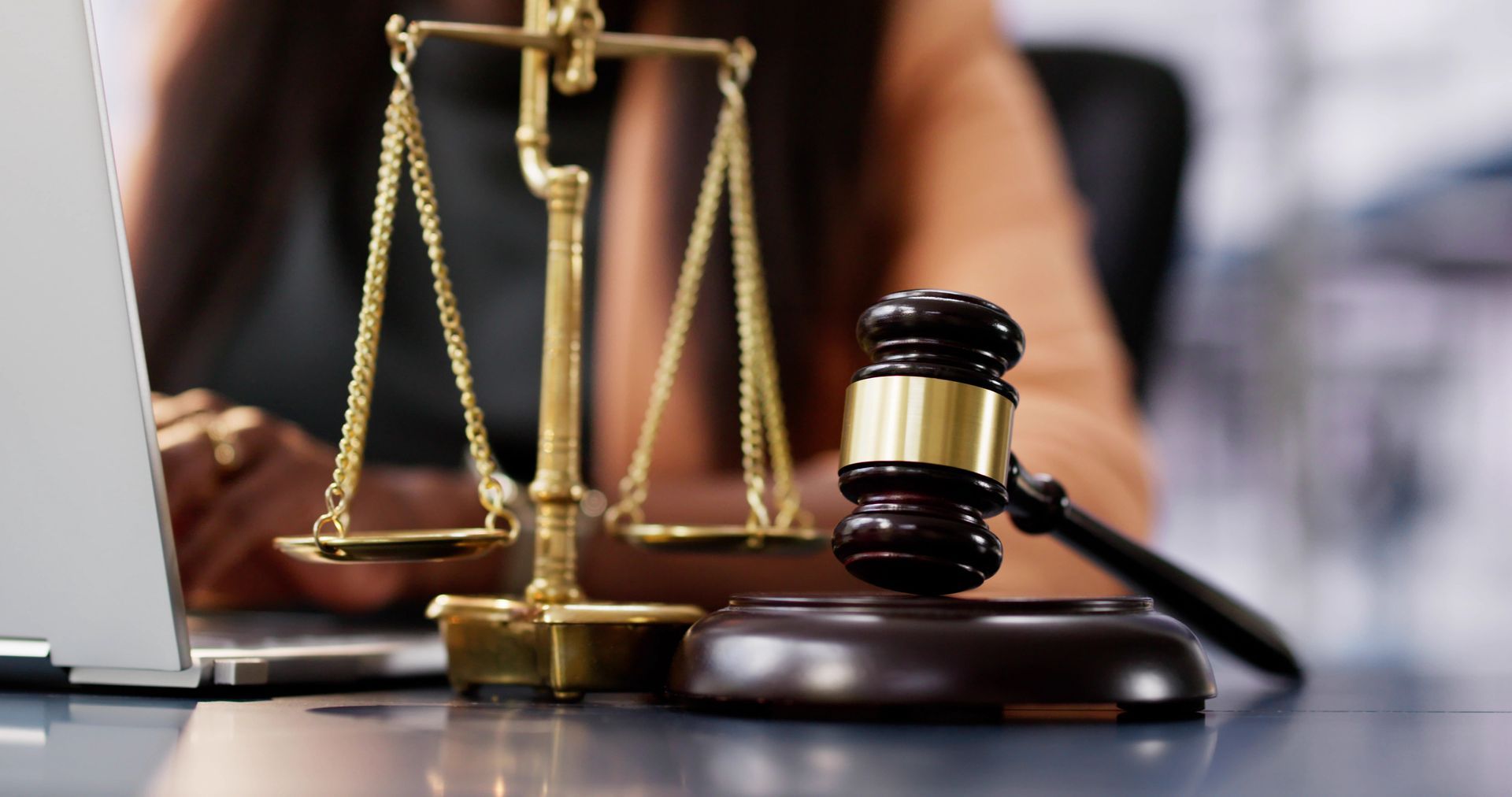 A judge 's gavel and scales of justice are on a table in front of a laptop computer.