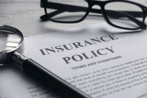 A magnifying glass is sitting on top of an insurance policy.