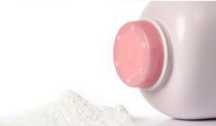 A bottle of baby powder with a pink cap and a pile of powder next to it.