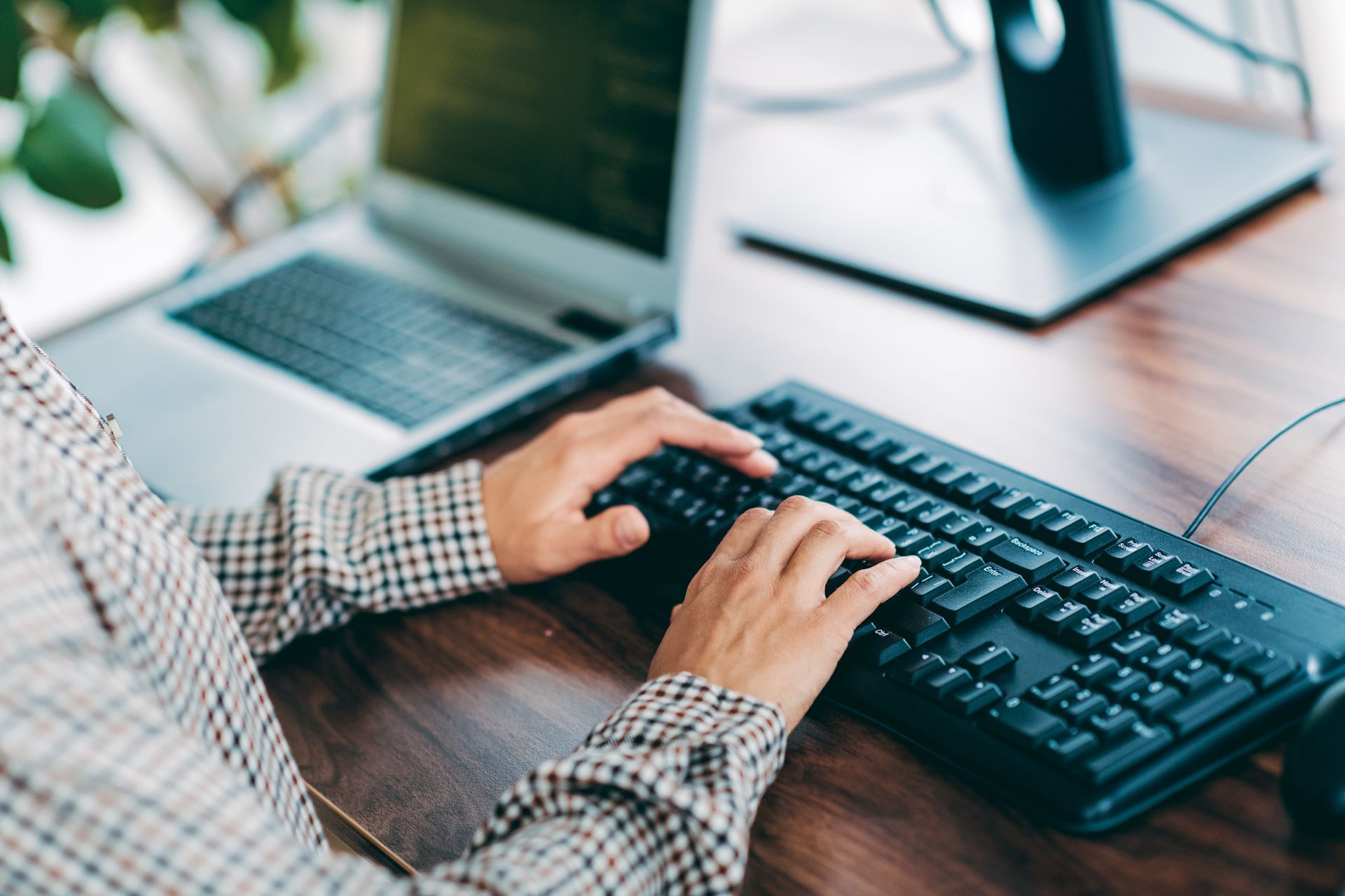 Close-up of hands typing on a keyboard at a computer workstation.