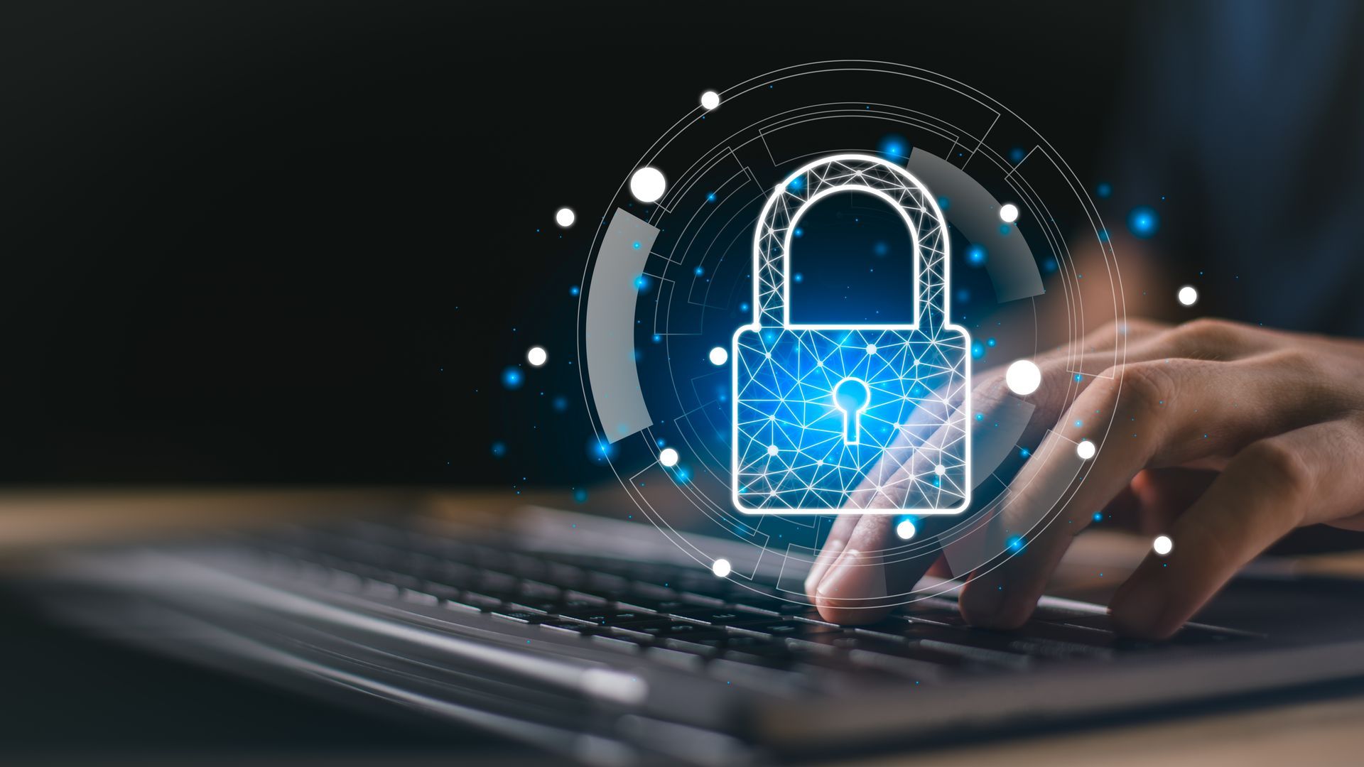 IT professional works on a laptop in a dimly lit server room. Person typing on laptop with digital padlock icon for IT security services