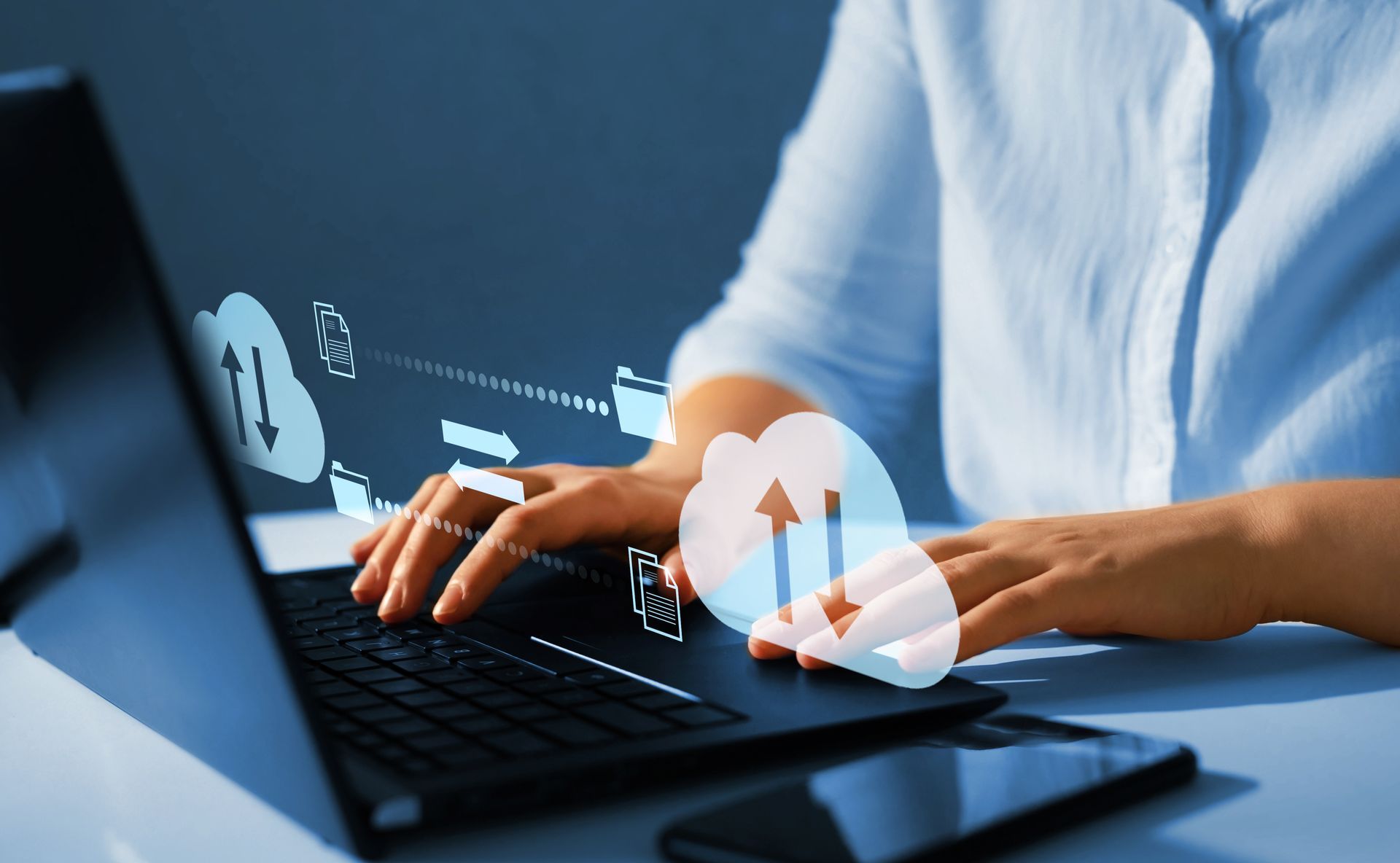 Hands typing on laptop with cloud upload and file transfer icons overlay.