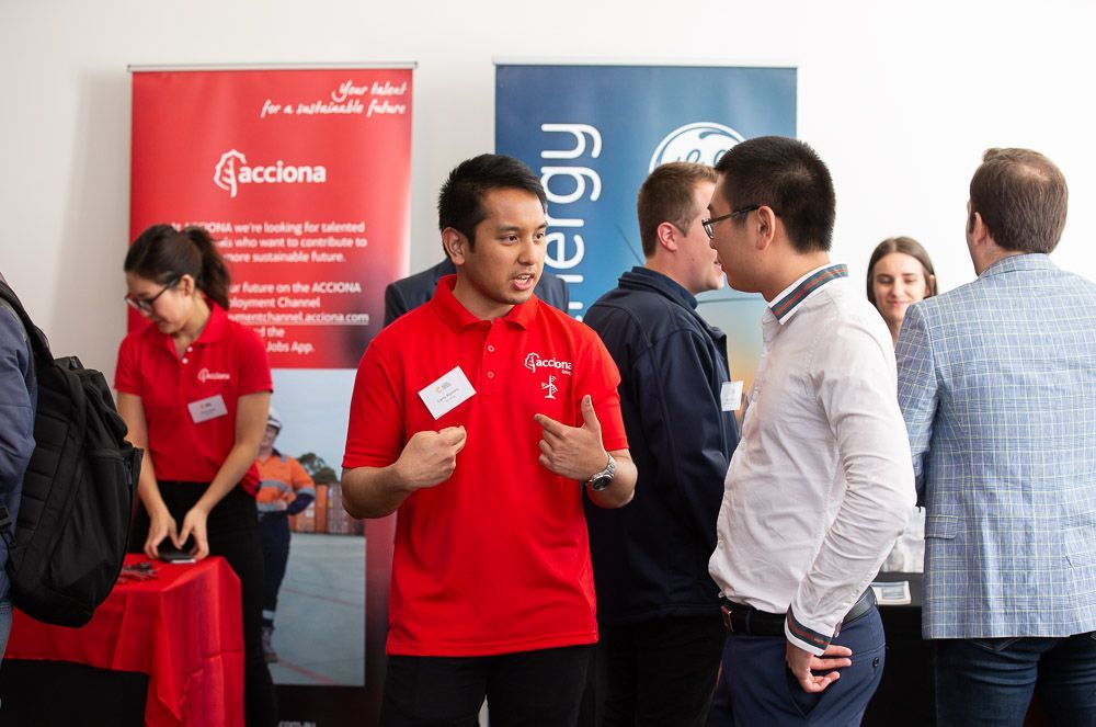 A man in a red shirt is talking to a group of people.