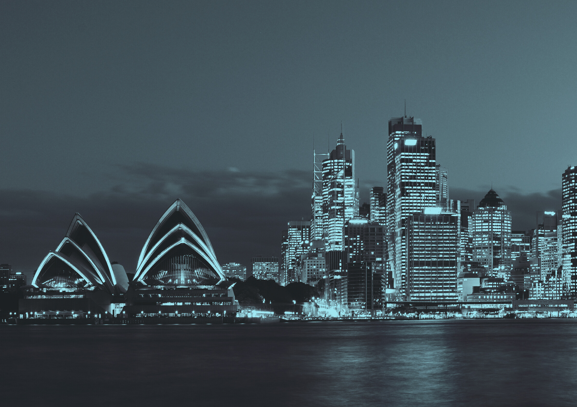 Sydney Opera House and city skyline illuminated at night.
