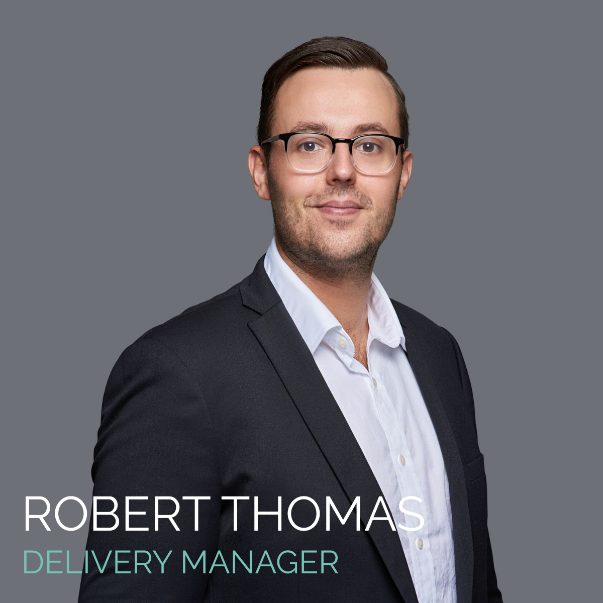 Robert Thomas, Delivery Manager, in a suit, smiles at the camera against a gray background.
