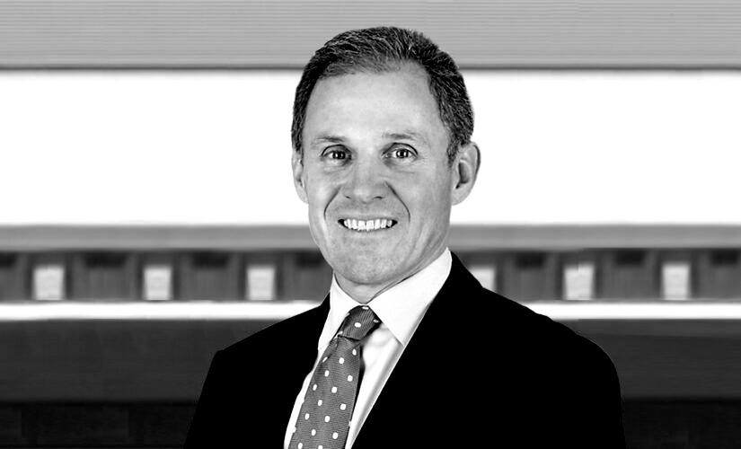 A man in a suit and tie is smiling in a black and white photo.