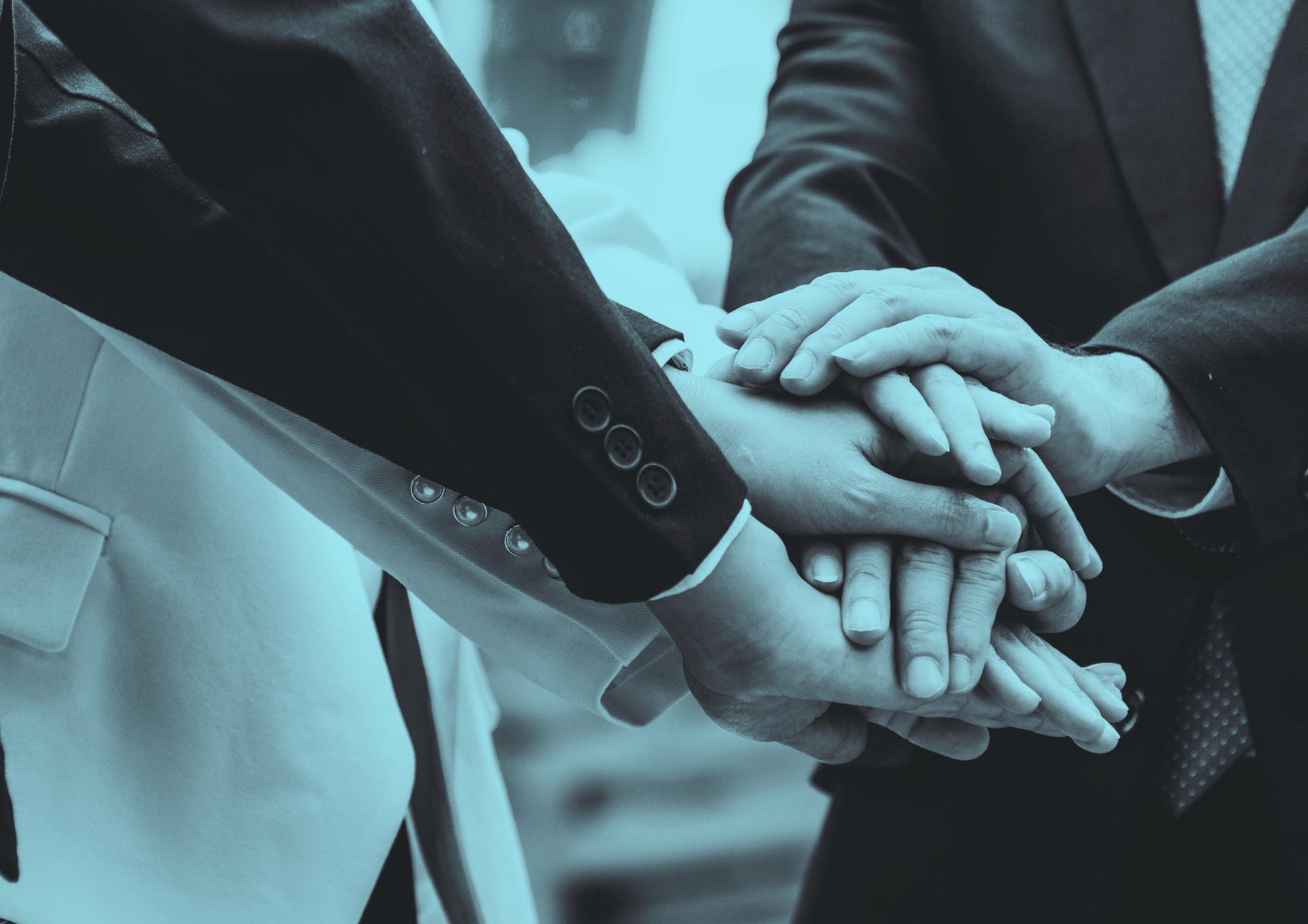 People's hands stacked together in a team huddle, symbolizing unity and collaboration.