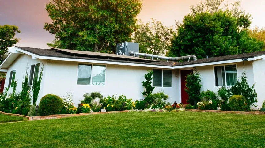 A white house with a lush green lawn in front of it