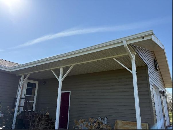 House exterior with beige siding, white porch posts, and a red door under a blue sky