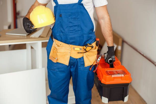 A construction worker is holding a hard hat and a toolbox.