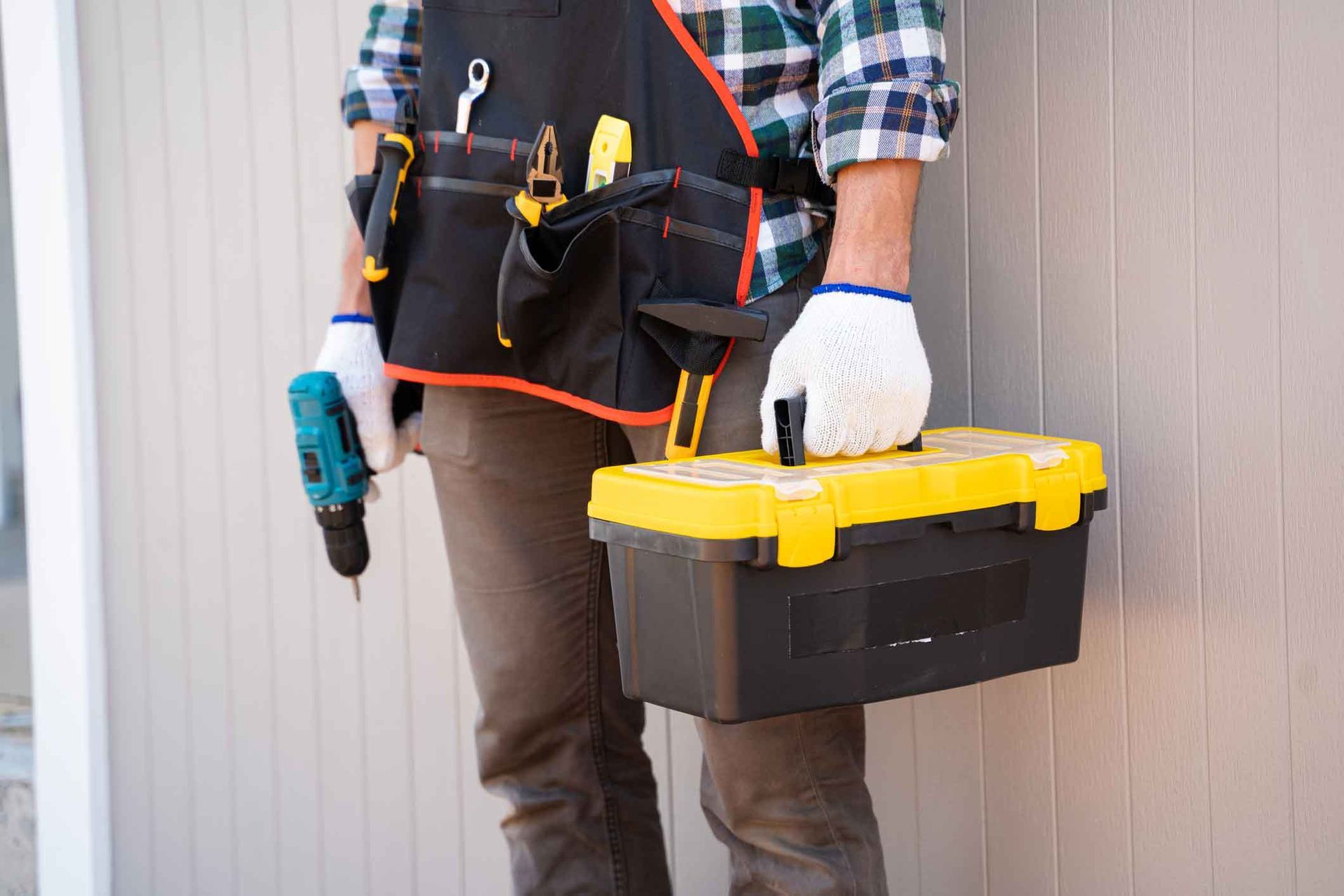 A man is holding a toolbox and a drill.