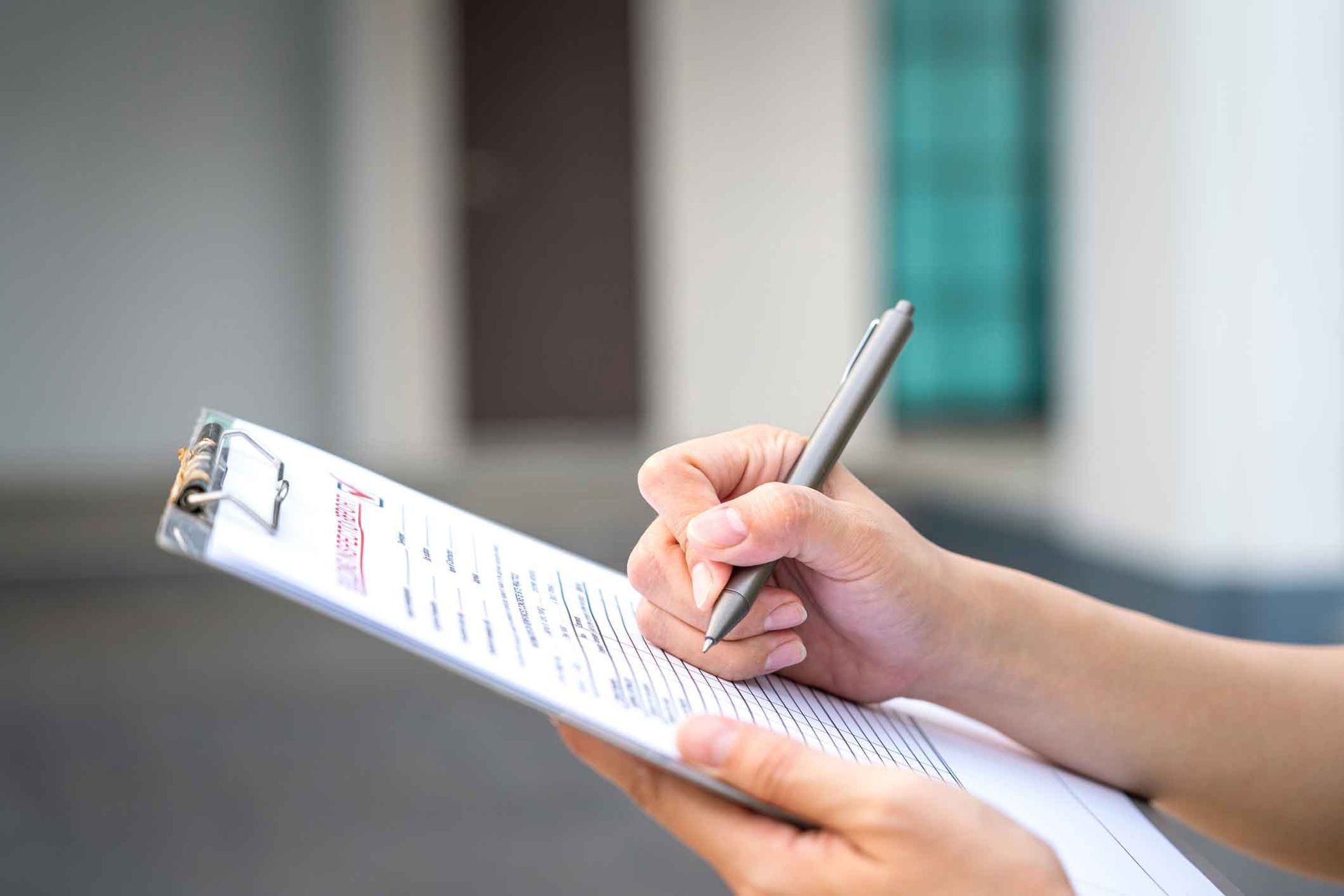 A person is writing on a clipboard with a pen.