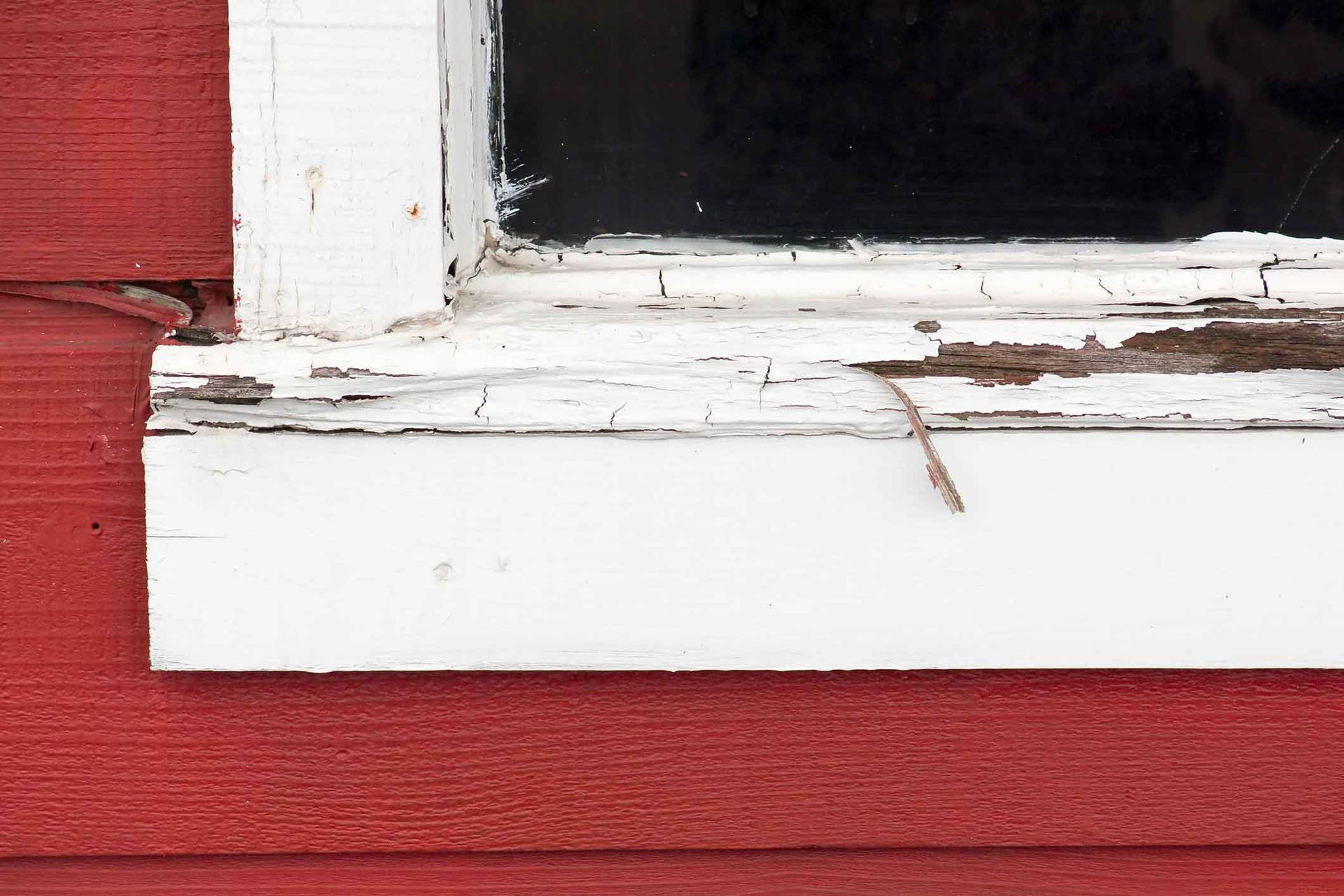 A white window frame is sitting on a red wall.