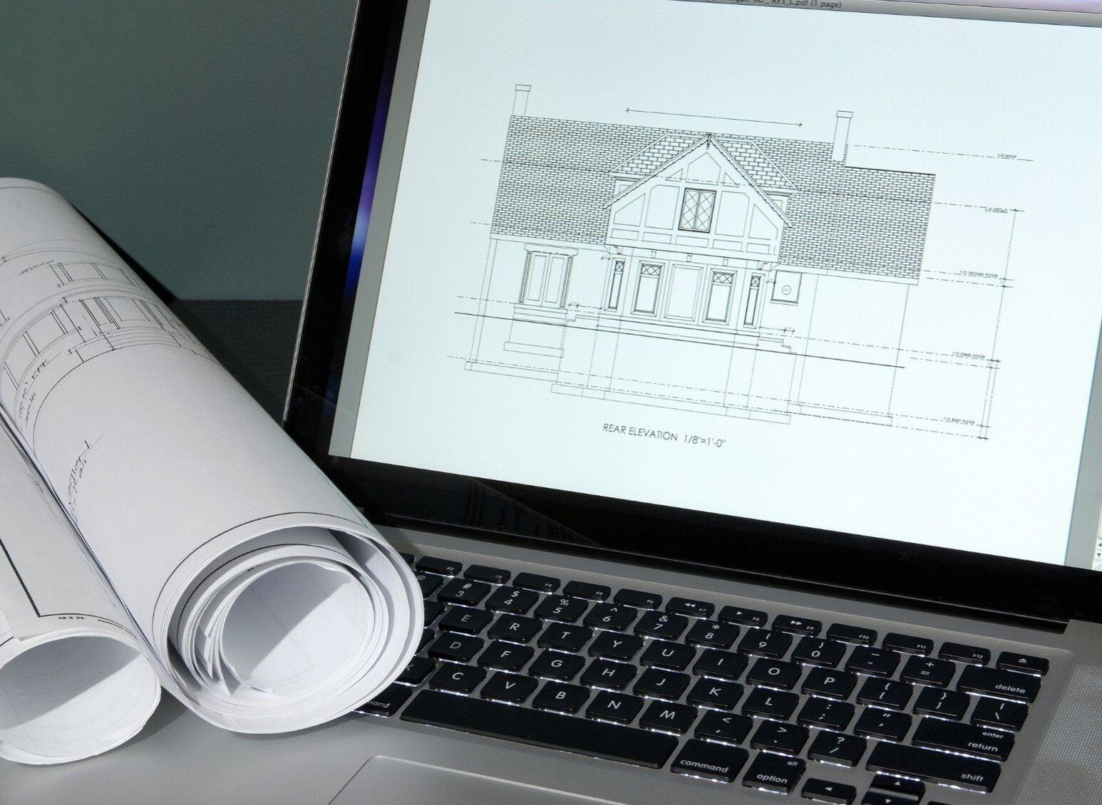 House elevations drawing shown on laptop with drawing roll beside
