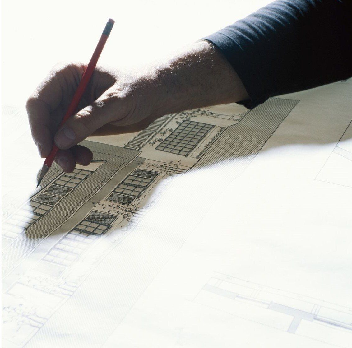 persons hand and shadow drawing on architectural drawing