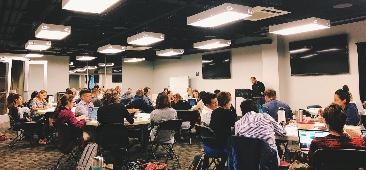 A large group of people are sitting at tables in a conference room.