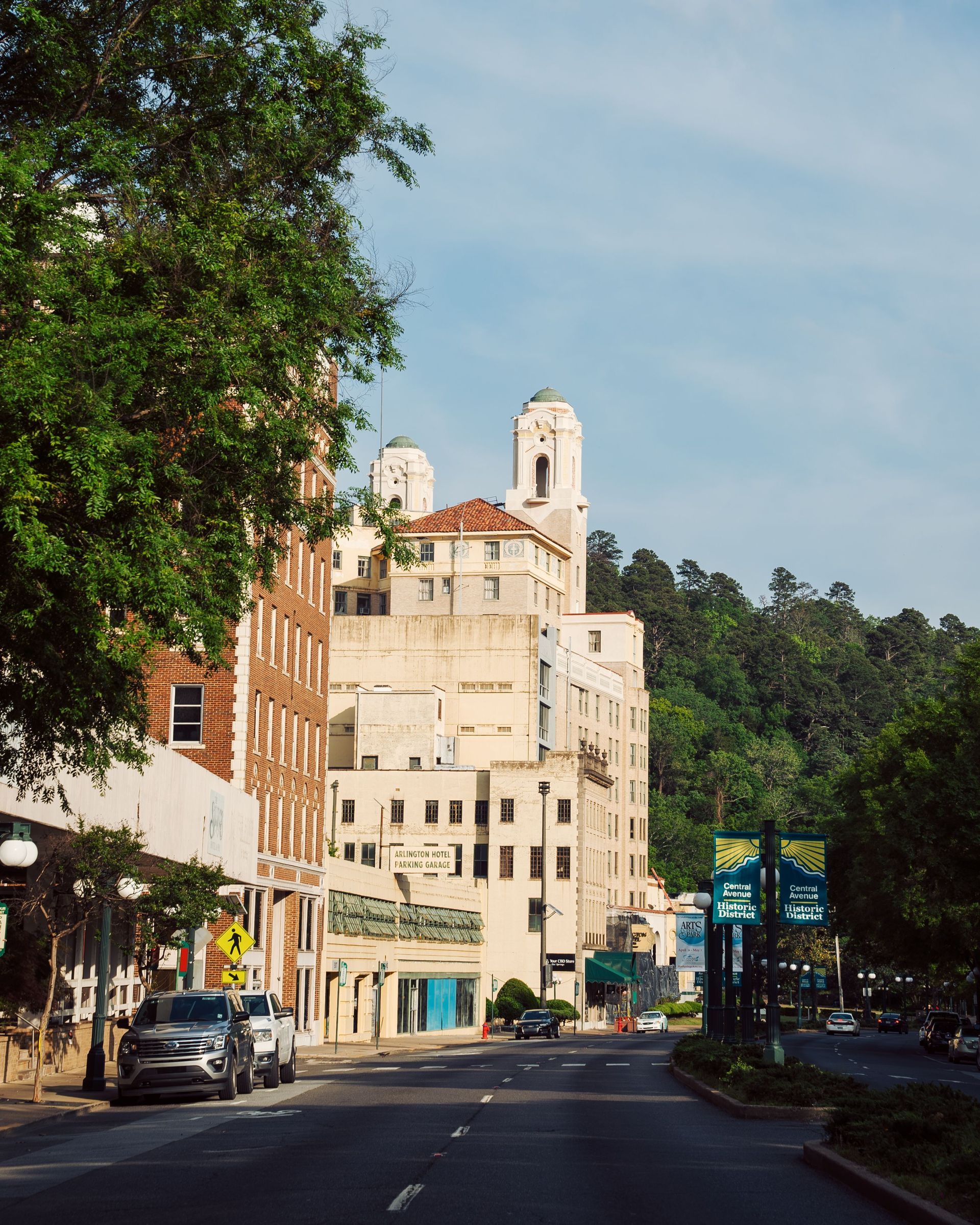 Sunlit street lined with tall buildings and trees on a gentle curve under a clear sky