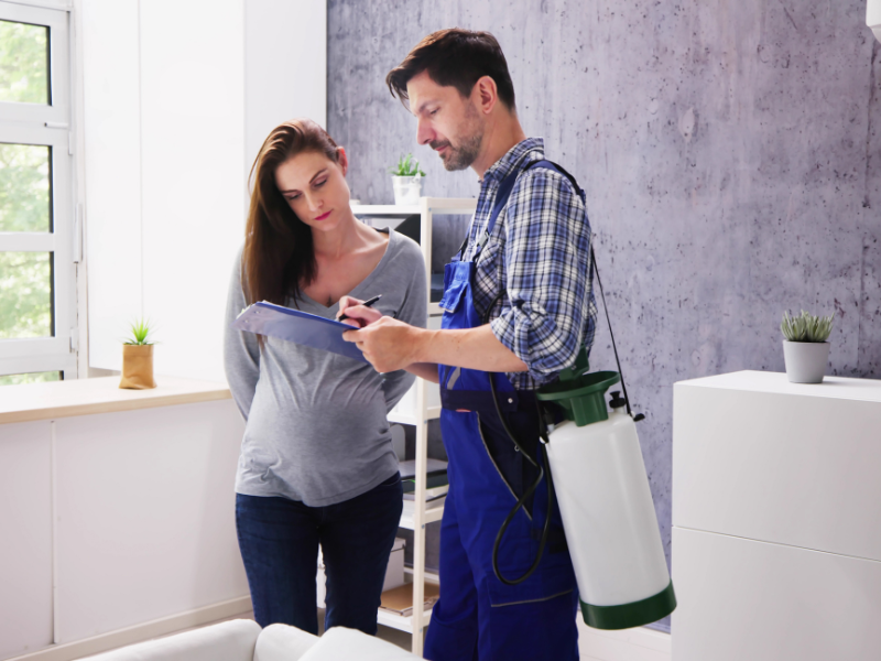 Une femme enceinte examine des documents avec un employé de la désinsectisation à l'intérieur de son domicile.