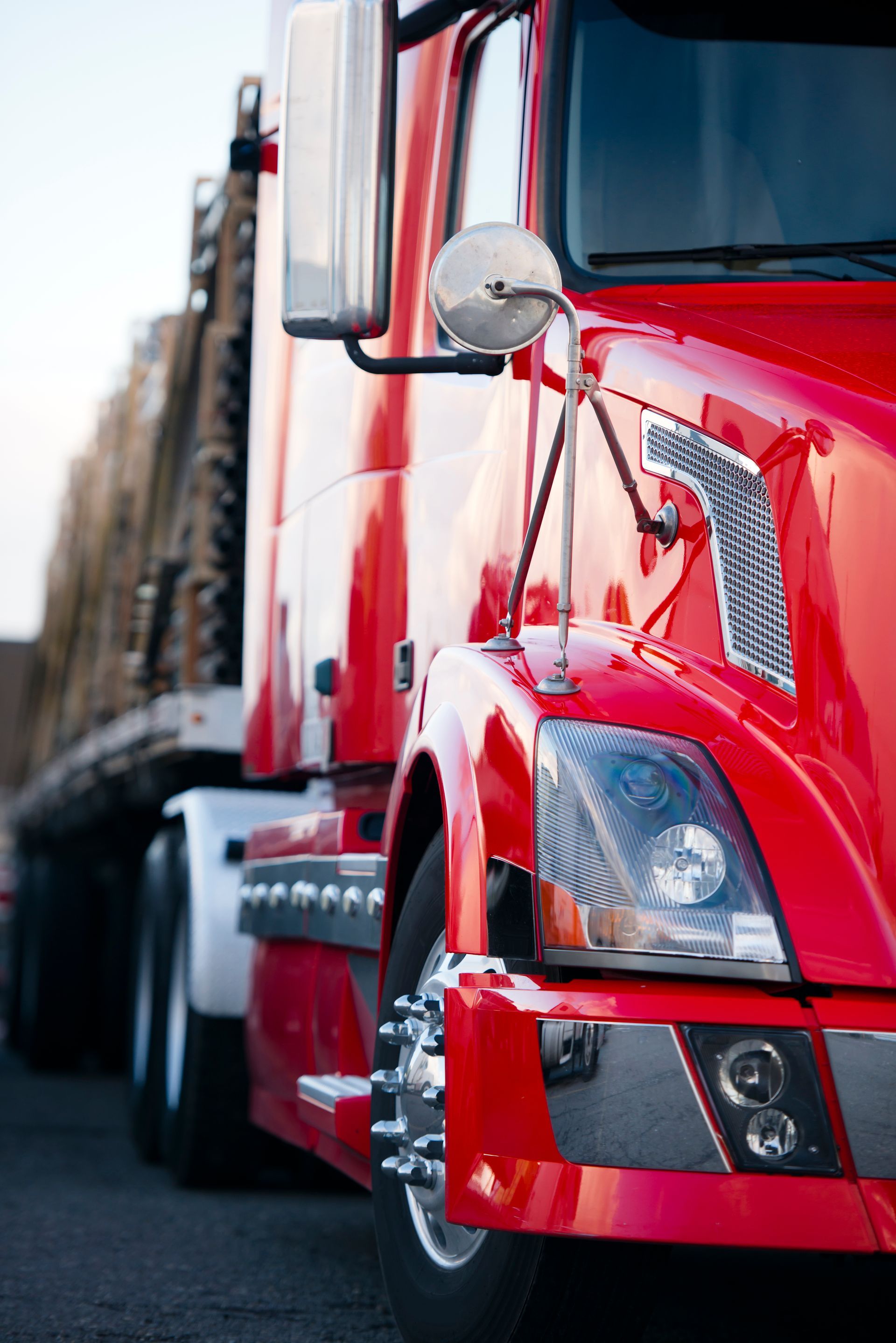 Red semi-truck cab parked with trailers on a road, close-up front view
