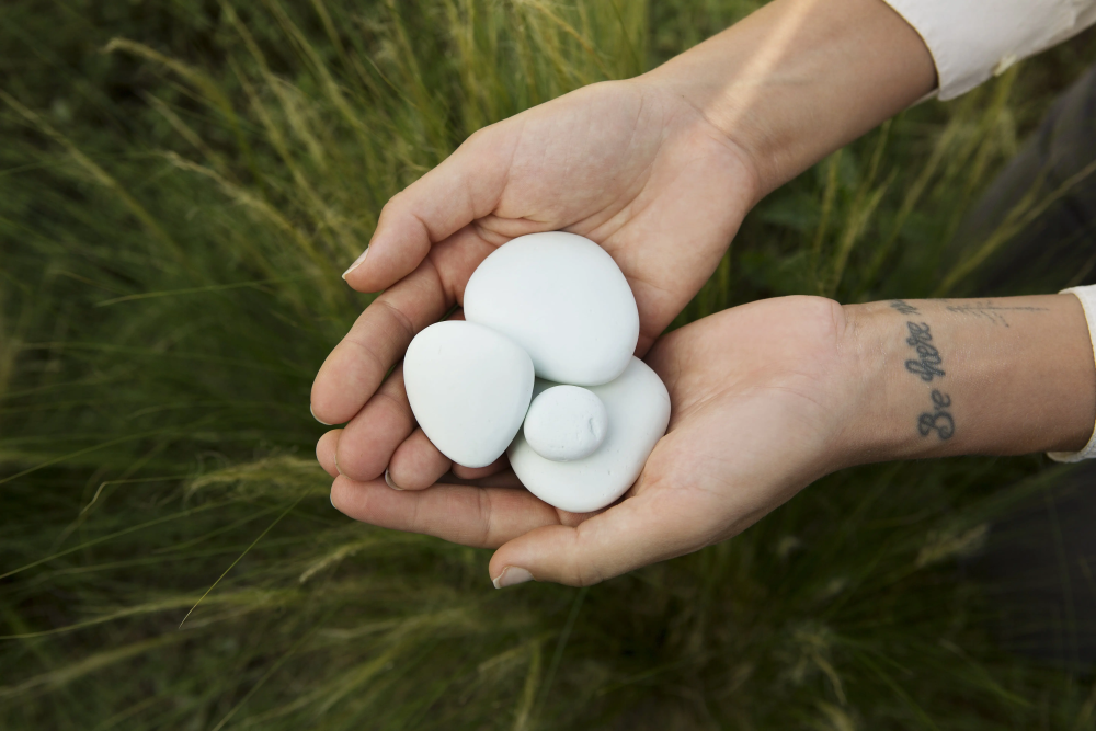 A person with a tattoo on their wrist is holding white rocks in their hands.
