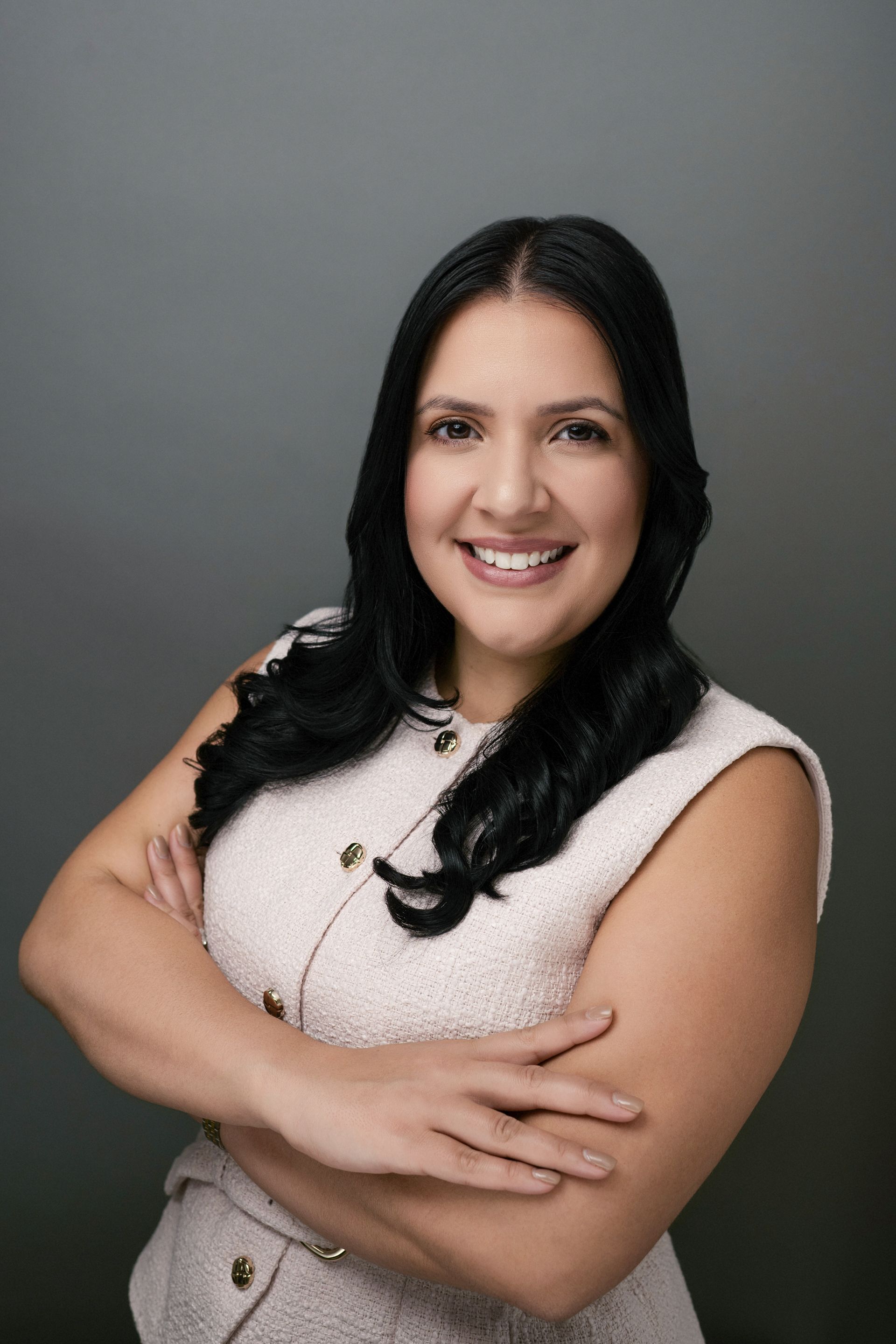 Caridad Cangas-Planas. A woman with dark hair, smiling and wearing a beige top.