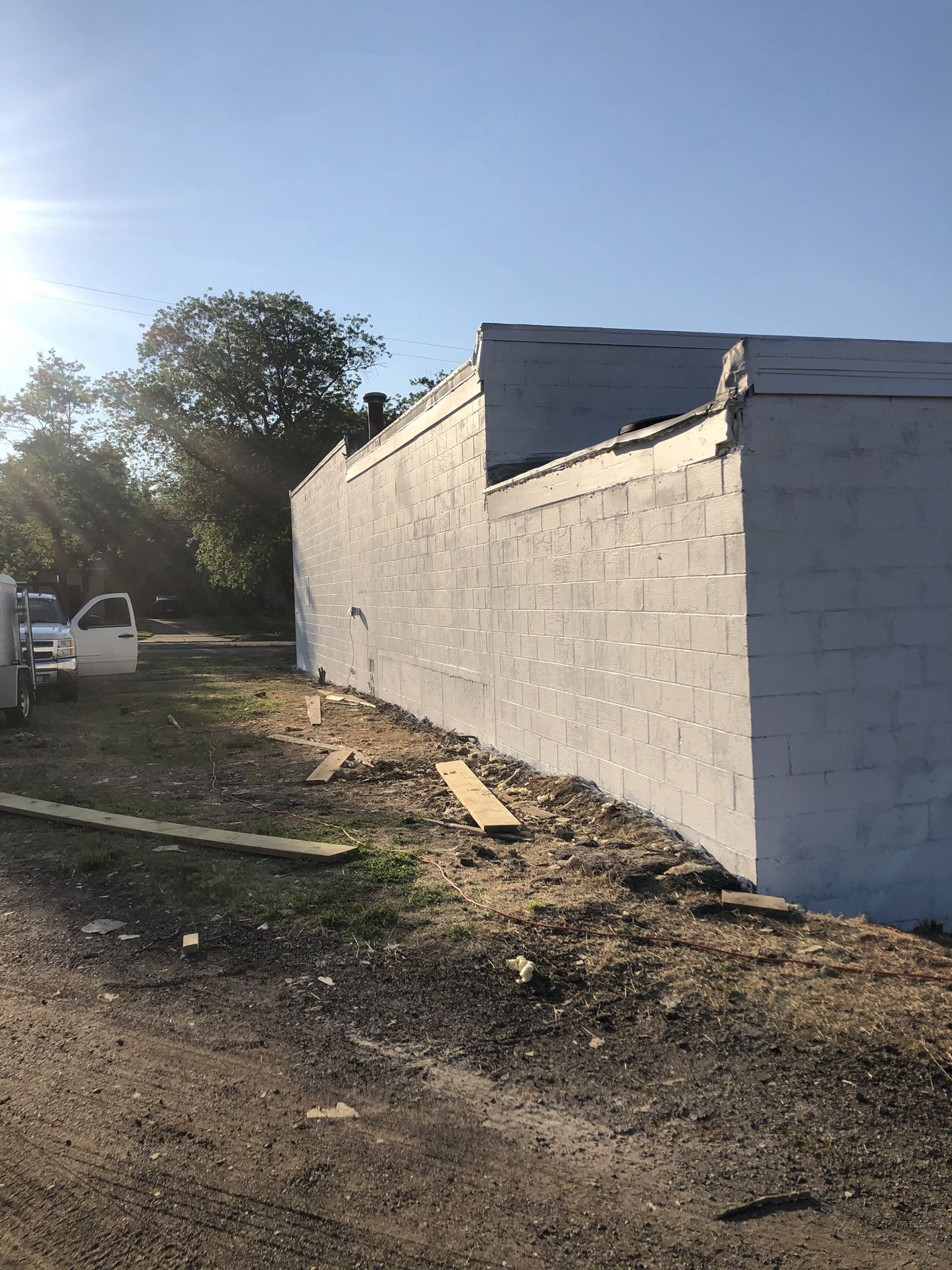A white truck is parked in front of a white brick wall.