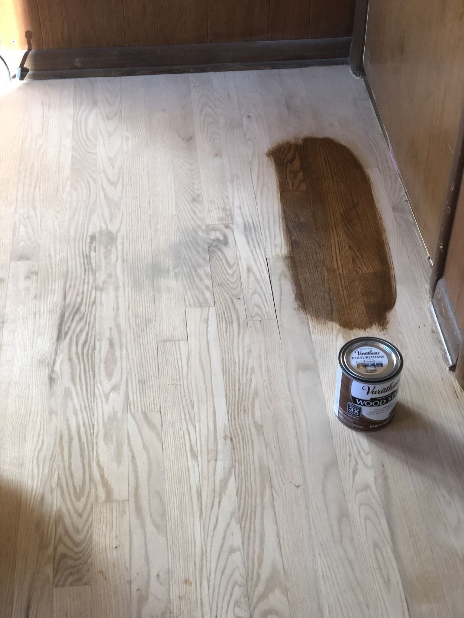 A can of paint is sitting on a wooden floor.